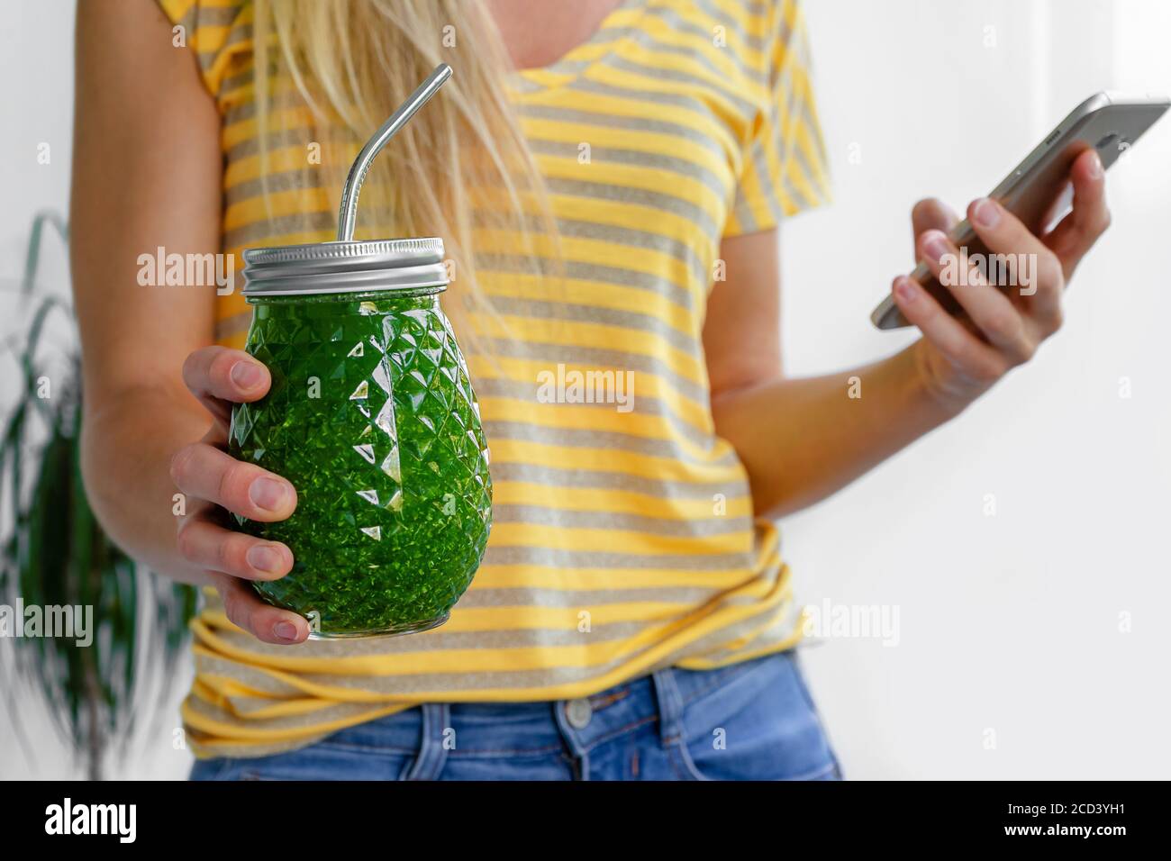 Femme caucasienne tenant un pot de smoothie vegan vert avec de la paille métallique. Concept de régime alcalin. Banque D'Images