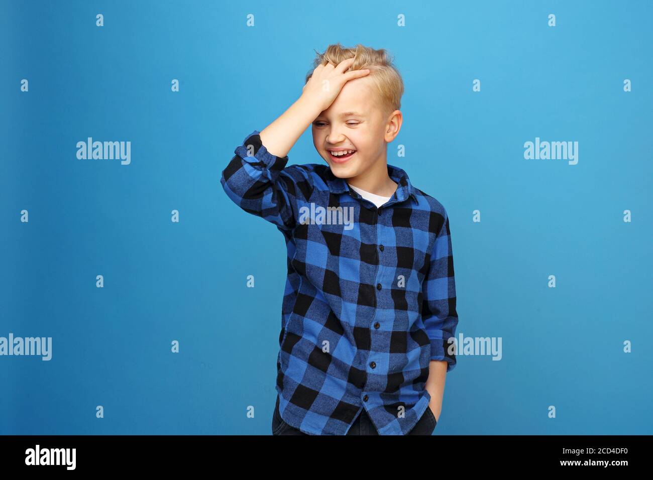 Garçon souriant, enfant heureux. Enfant heureux, rire garçon. Un garçon heureux et souriant sur fond bleu exprime ses émotions par des gestes. Banque D'Images