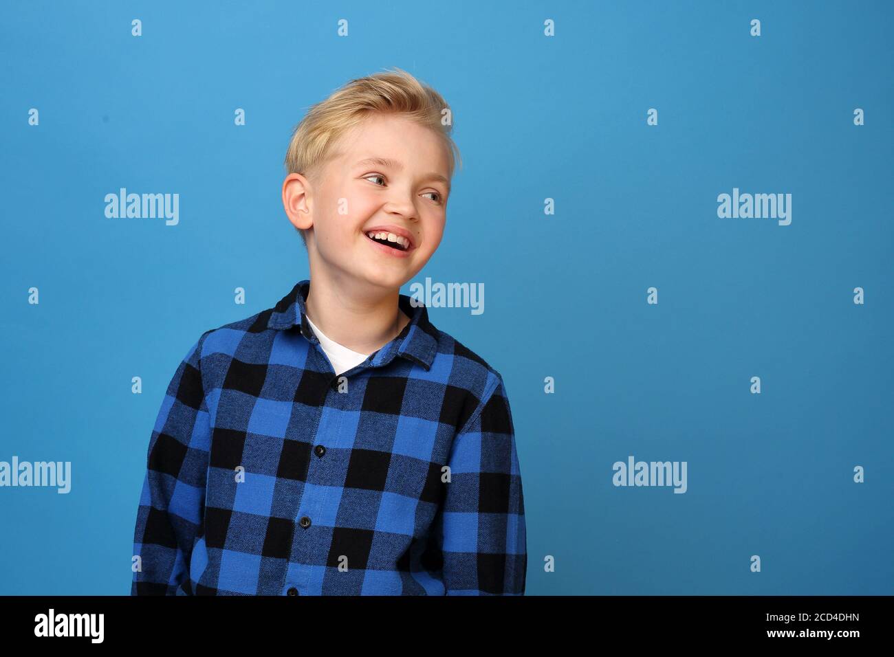 Garçon souriant, enfant heureux. Enfant heureux, rire garçon. Un garçon heureux et souriant sur fond bleu exprime ses émotions par des gestes. Banque D'Images