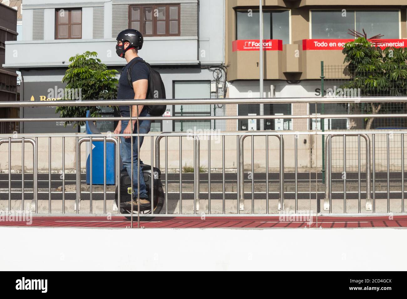 Homme portant une couverture de visage à cheval sur une roue électrique mono, auto-équilibrant tricycle électrique sur piste cyclable en Espagne Banque D'Images