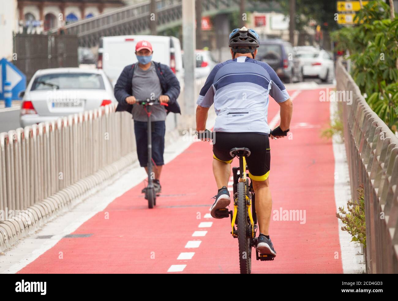 Cycliste et scooter électrique sur une piste cyclable séparée de la circulation. Espagne Banque D'Images