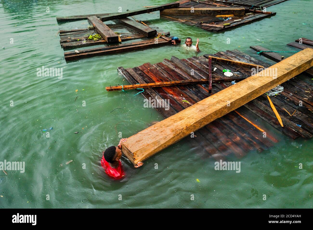 Un transporteur colombien pousse un bois scié brut tout en nageant dans l'eau pendant le transport du bois à Turbo, en Colombie. Banque D'Images