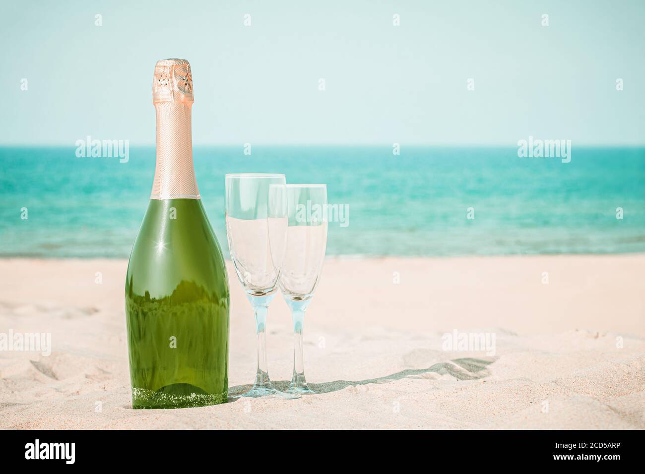 Deux verres et une bouteille de champagne sur sable blanc sur le fond de l'océan Banque D'Images