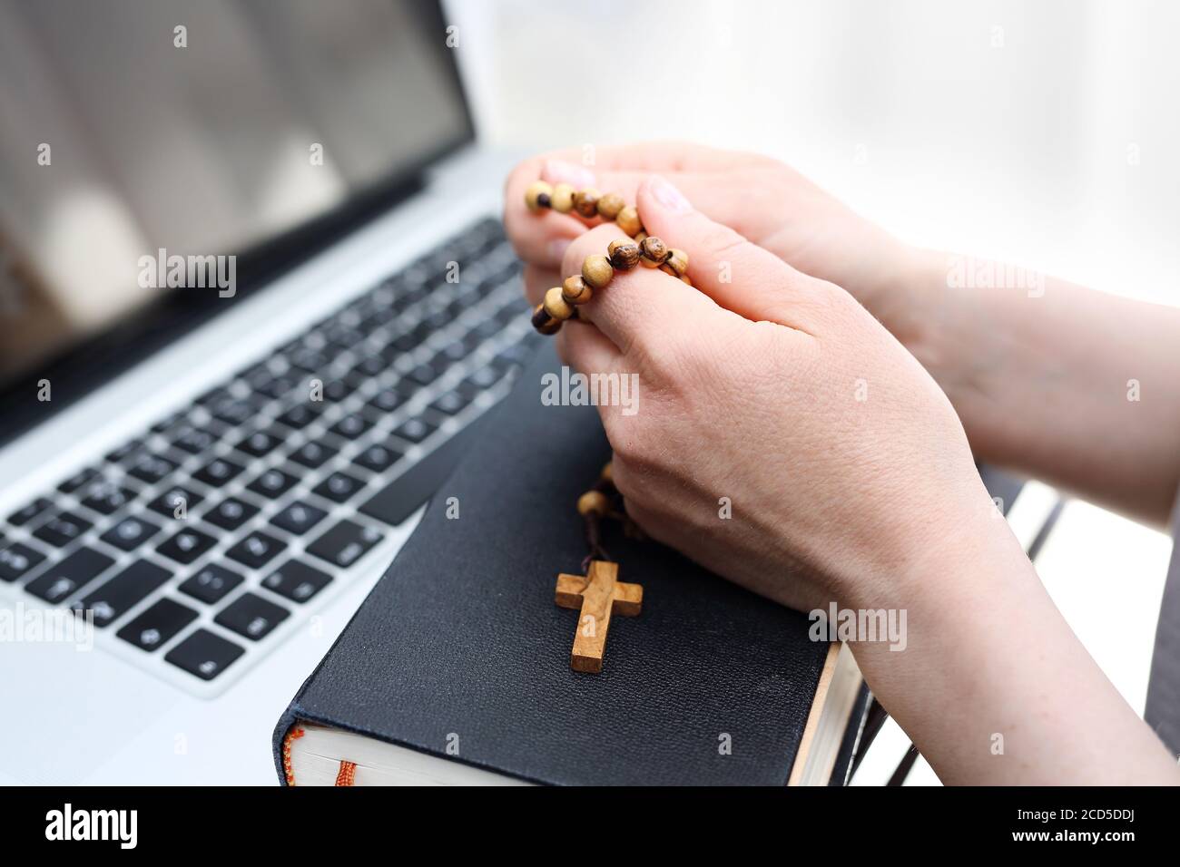 Masse catholique en ligne. Foi et prière. Une femme prie le rosaire. Une femme prie sur un rosaire devant un ordinateur. Banque D'Images
