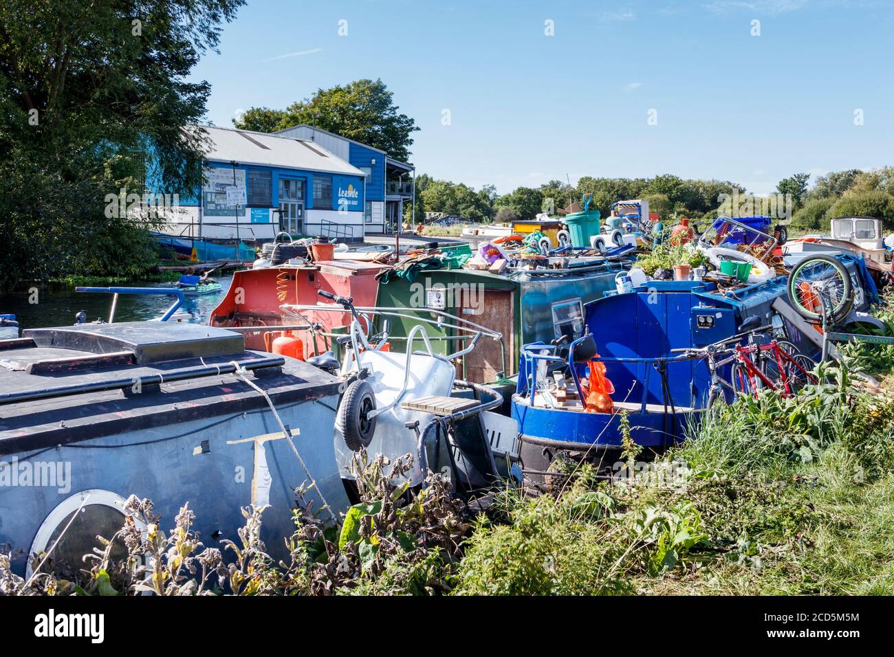 Des barques à la truelle amarrées sur la rivière Lea, leurs toits encombrés d'équipements utiles, Clapton, Londres, Royaume-Uni Banque D'Images