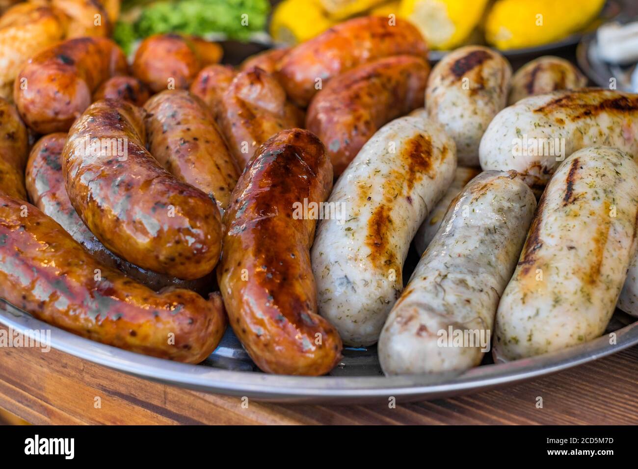 Saucisses fraîches et des hot-dogs sur le gril en plein air sur un barbecue à gaz. Banque D'Images
