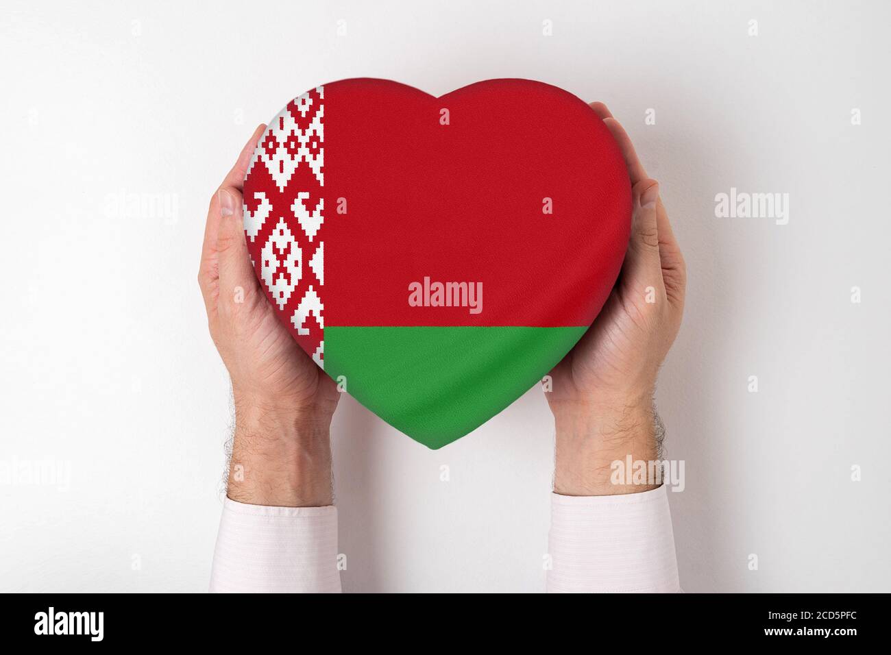 Drapeau de la Biélorussie sur une boîte en forme de coeur dans les mains d'un homme. Arrière-plan blanc Banque D'Images