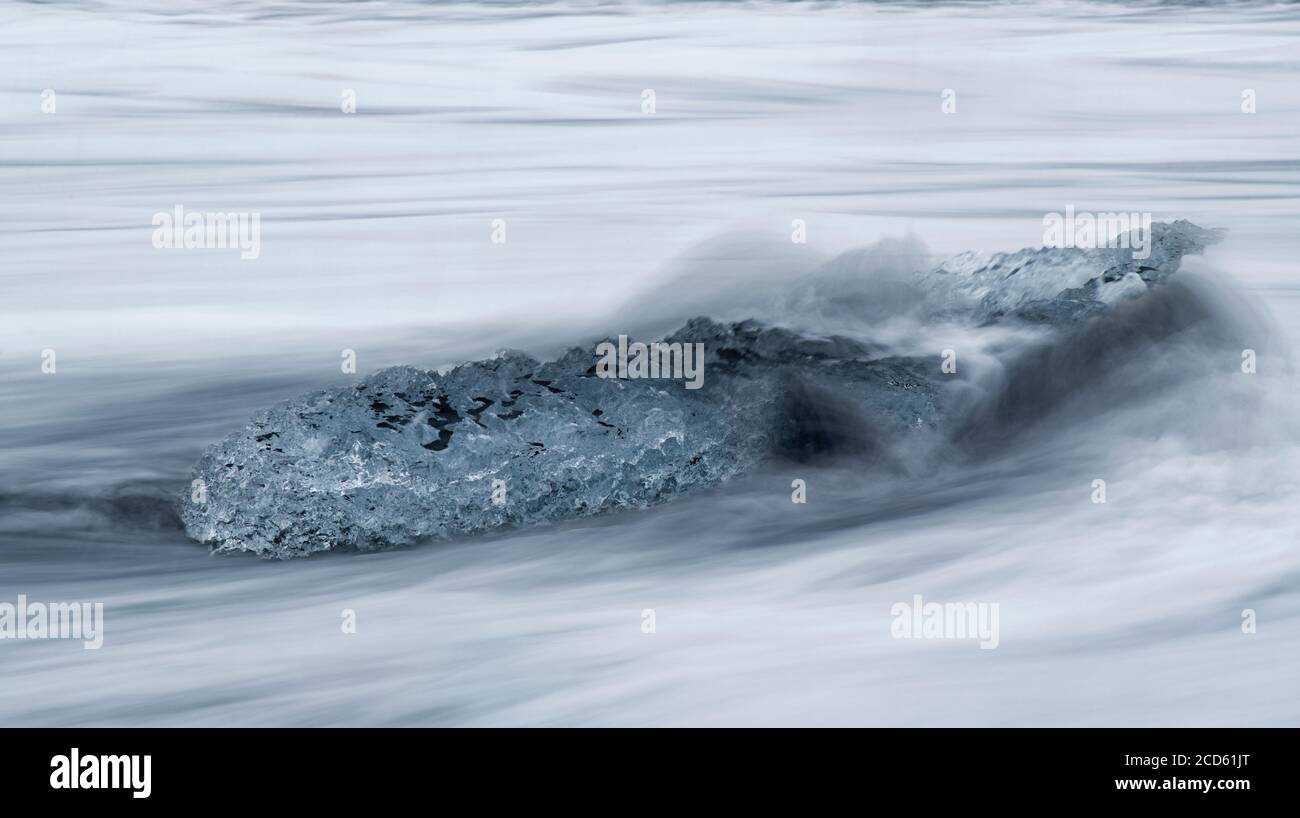 Vagues éclaboussant sur glace sur la plage, Islande Banque D'Images