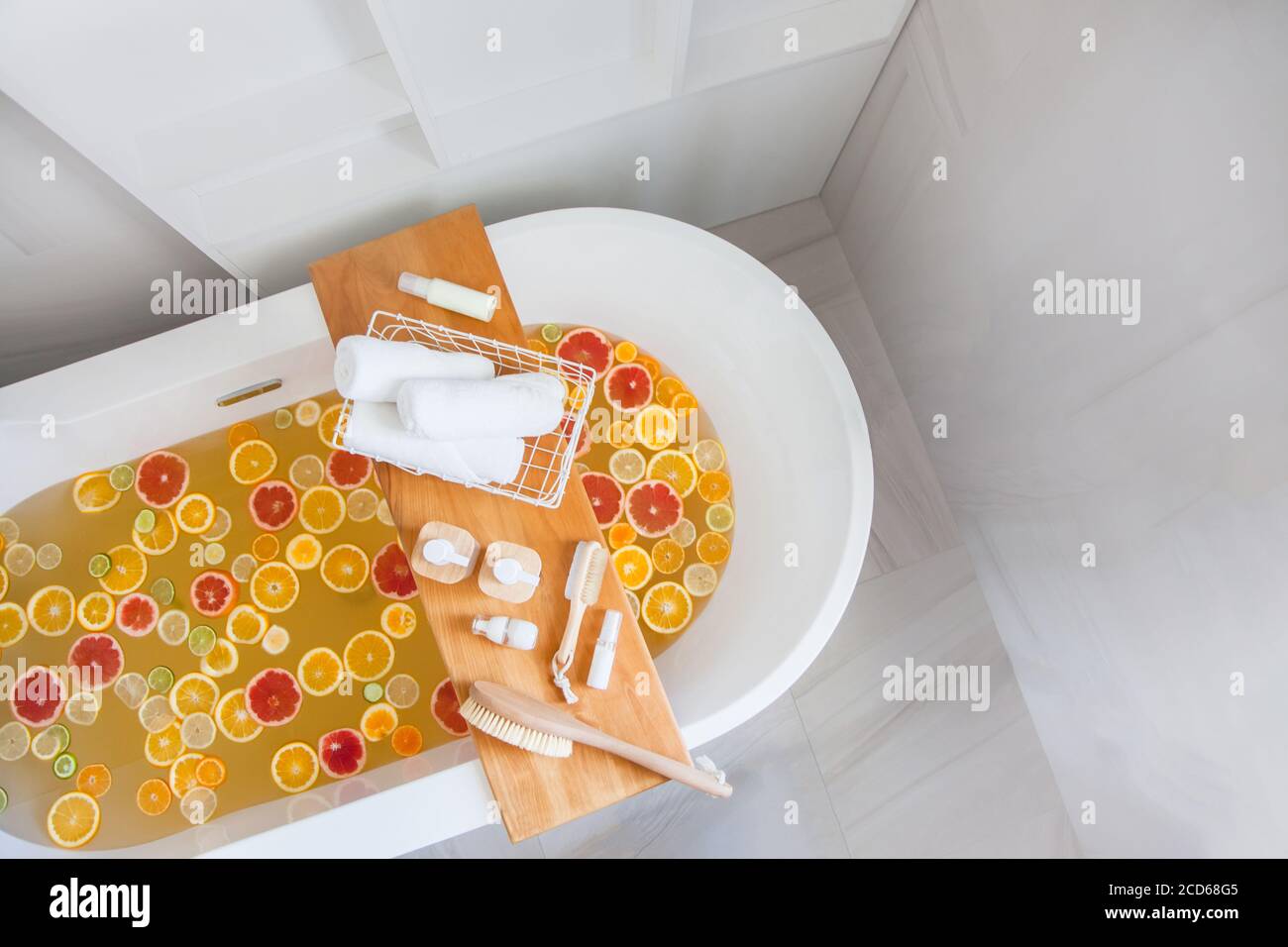 Baignoire avec un mélange de tranches d'agrumes frais et un ensemble spa de produits naturels. Banque D'Images