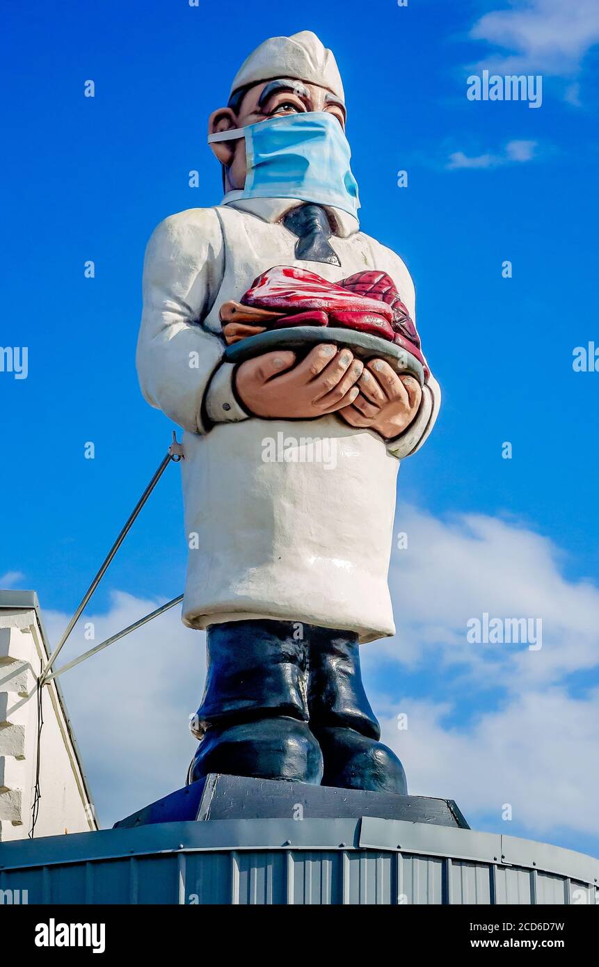 La statue du boucher sur le toit du marché de Cannata porte un masque lors de la pandémie COVID-19, le 25 août 2020, à Morgan City, en Louisiane. Banque D'Images
