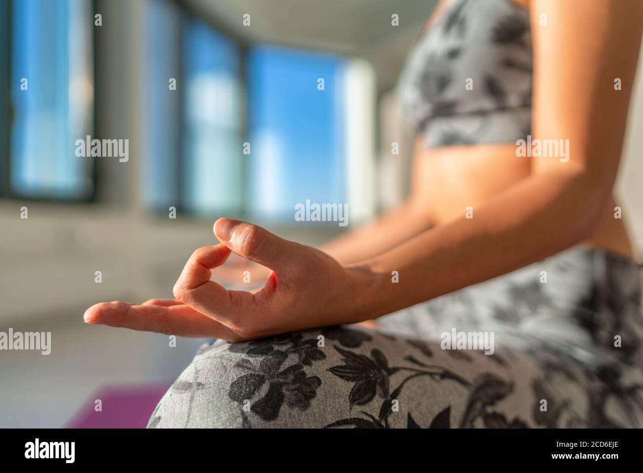 Cours de yoga à la salle de gym femme méditant avec la mudra de main dans la pose de lotus au soleil du matin. Yoga pratique méditation vie saine à la maison style de vie Banque D'Images