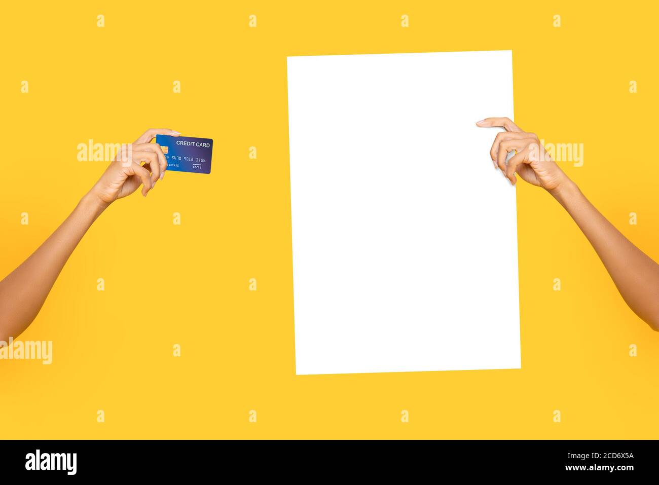 Mains de femmes portant du papier d'affichage blanc vide et des cartes de crédit sur bakground jaune studio isolé Banque D'Images