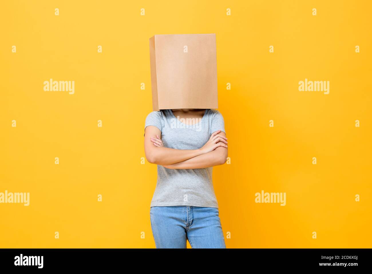 Portrait de concept de la femme anonyme avec la tête couverte de papier sac faisant des bras mouvement croisé sur fond jaune studio Banque D'Images