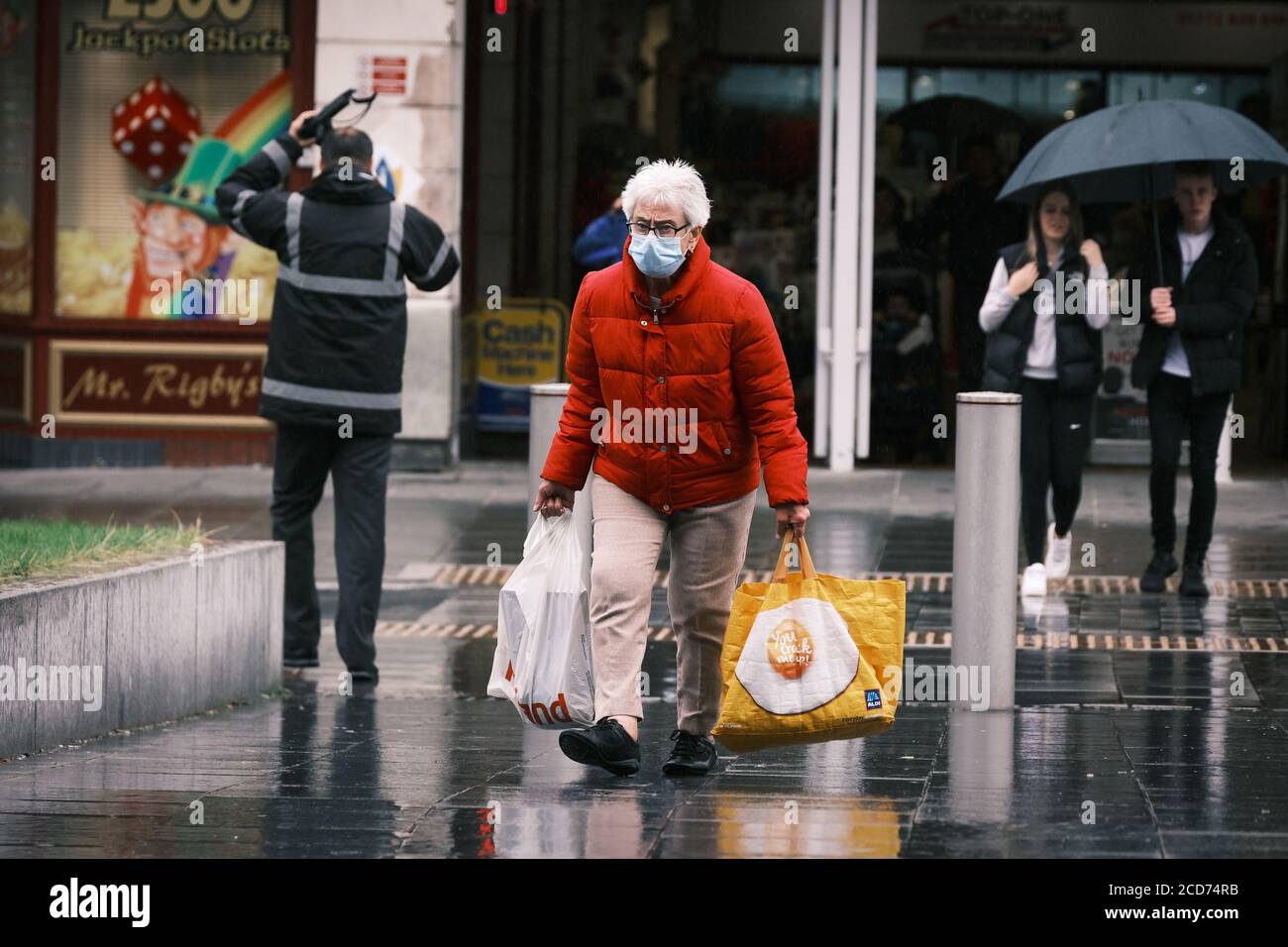 Météo au Royaume-Uni: Homme avec des sacs d'achats pris dans la douche de pluie, Preston, Royaume-Uni. Banque D'Images
