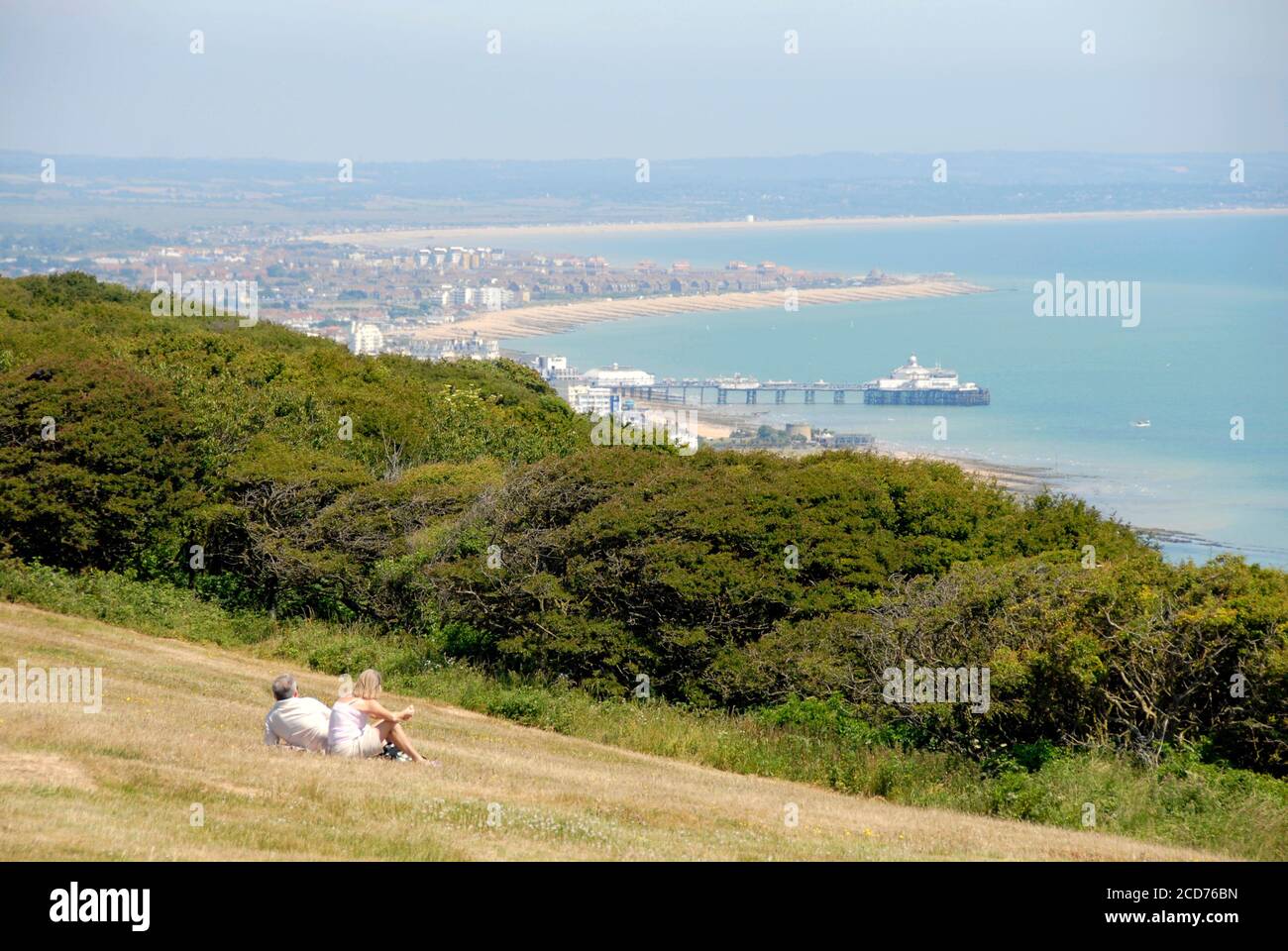 Deux personnes assises sur l'herbe en regardant vers Eastbourne, au loin de Beachy Head, East Sussex, Angleterre Banque D'Images