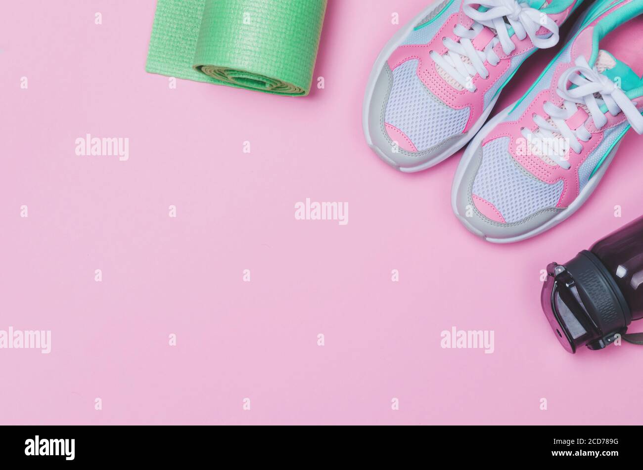 Tapis de yoga, chaussures de sport, bouteille d'eau sur fond rose. Un mode de vie sain. Copier l'espace Banque D'Images