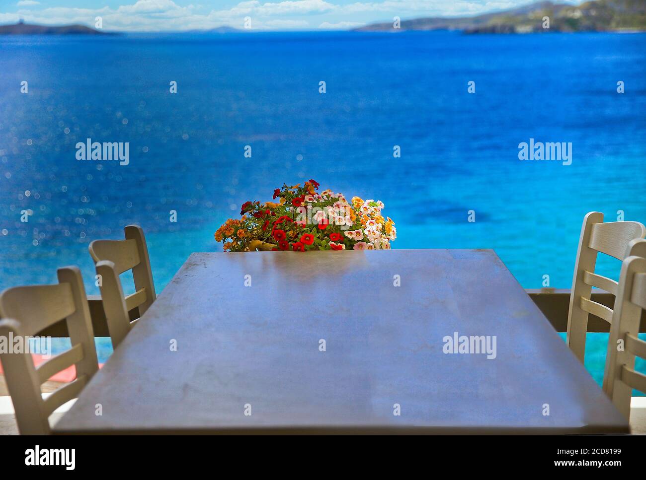 Table et chaises. Table avec un bouquet de fleurs surplombant la mer Méditerranée. Image de stock. Banque D'Images