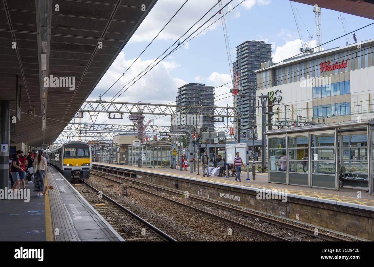 Plates-formes de la gare de Stratford avec un train entrant dans la plate-forme. Centre commercial Westfield en arrière-plan. Londres Banque D'Images