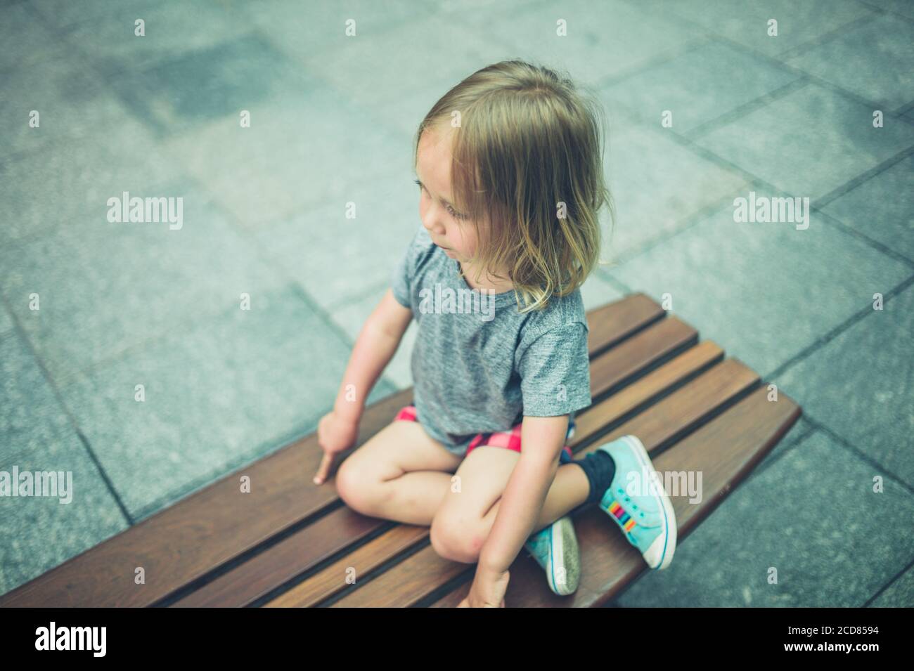 Un petit Preschooler est assis sur un banc dans le ville Banque D'Images