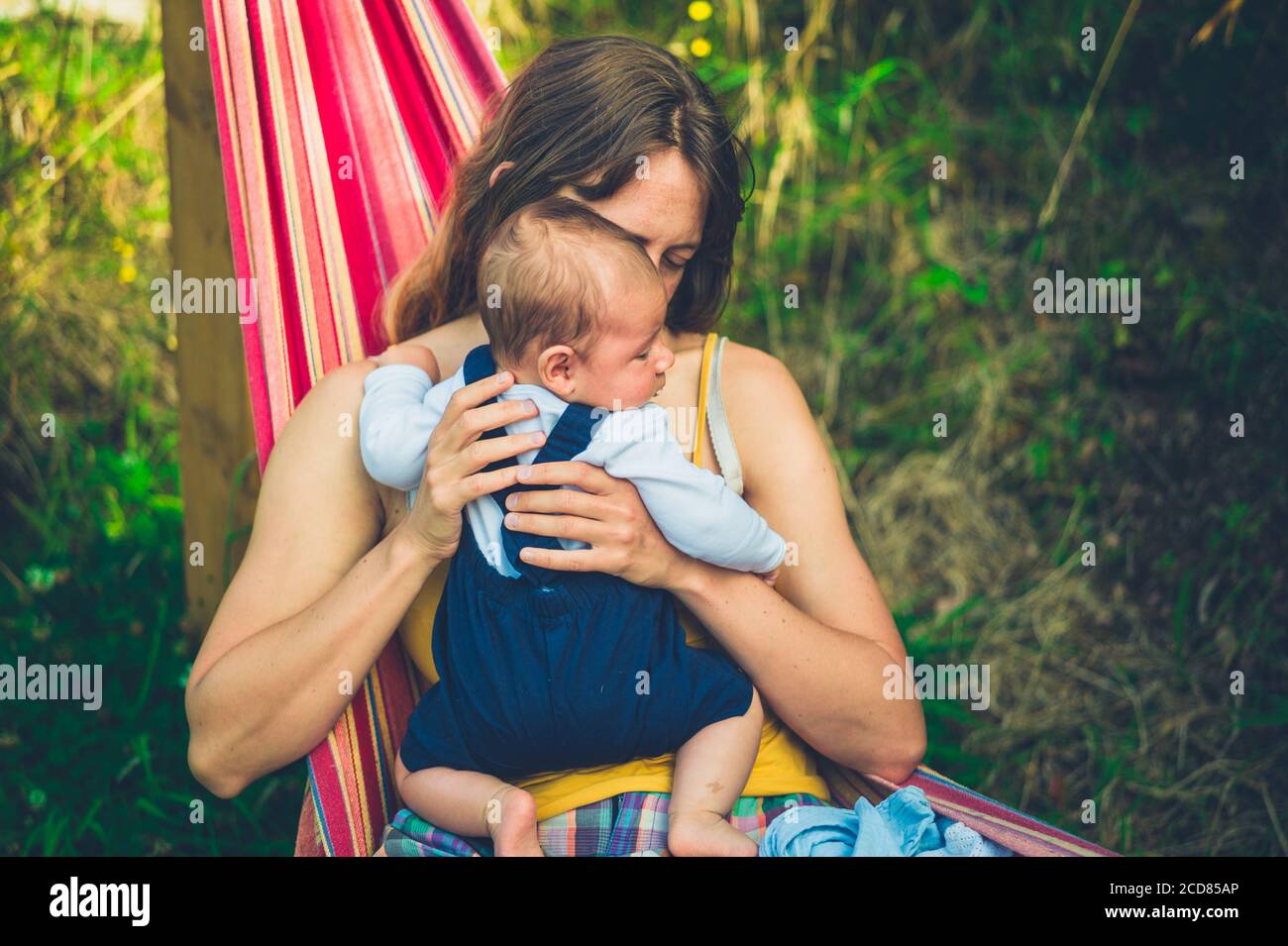 Une jeune mère est assise dans un hamac avec elle bébé en été Banque D'Images
