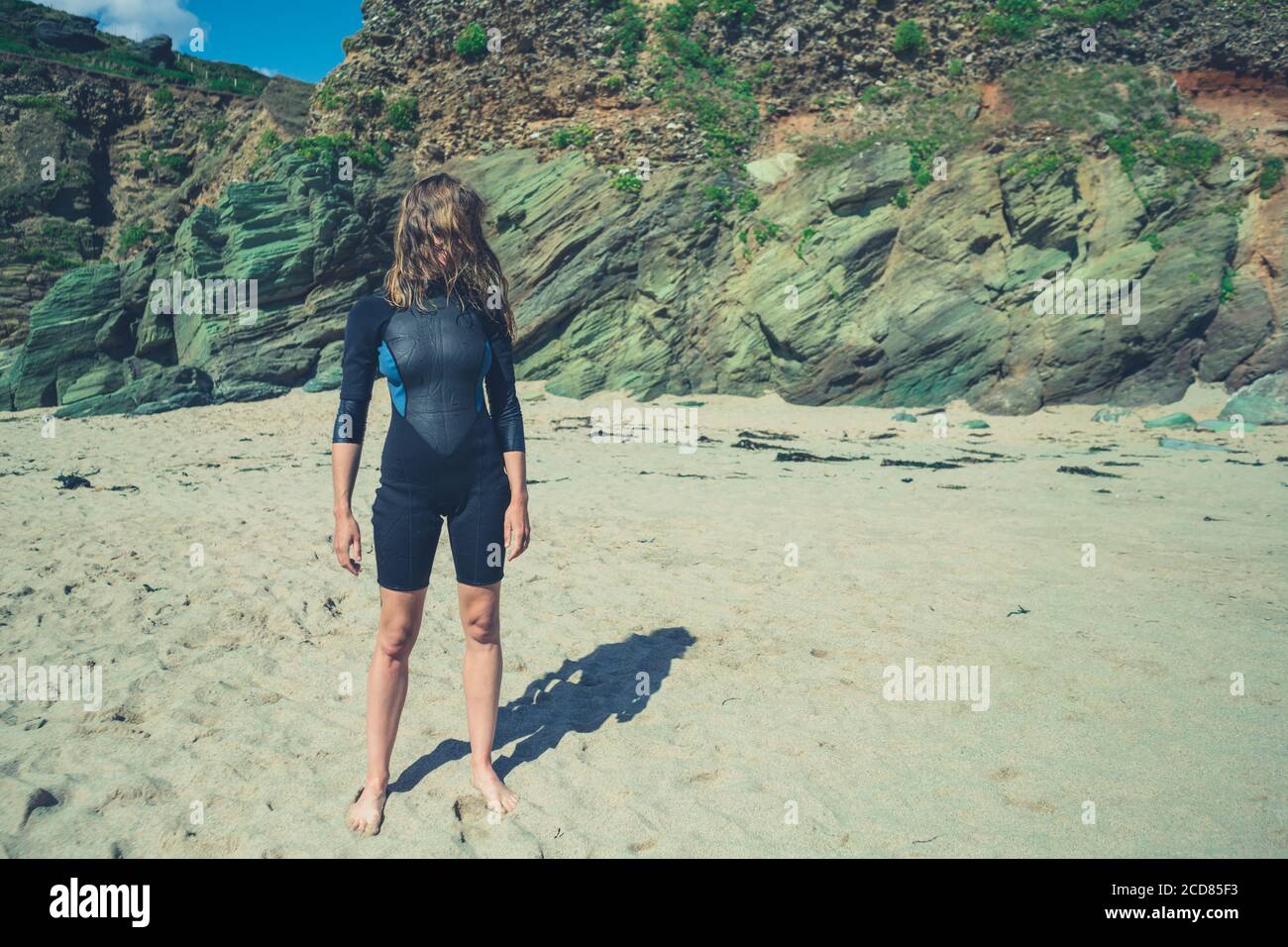Une jeune femme portant une combinaison isothermique est debout sur la plage en été Banque D'Images