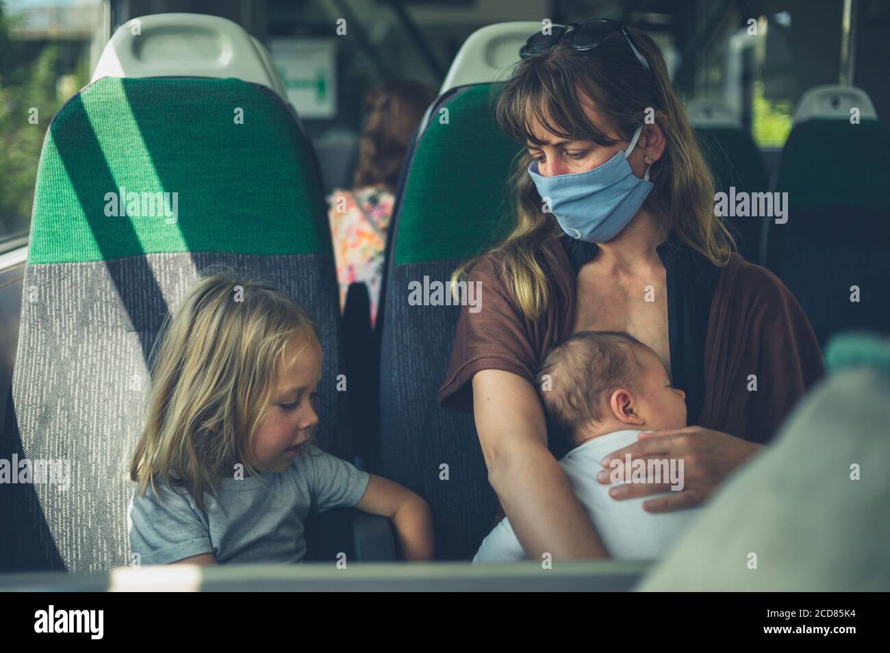 Une mère avec deux jeunes enfants porte un visage masque sur le train Banque D'Images