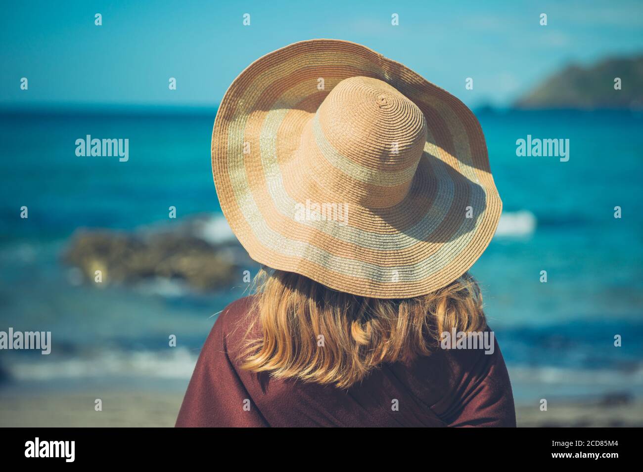 Une jeune femme porte un chapeau de paille par le mer en été Banque D'Images