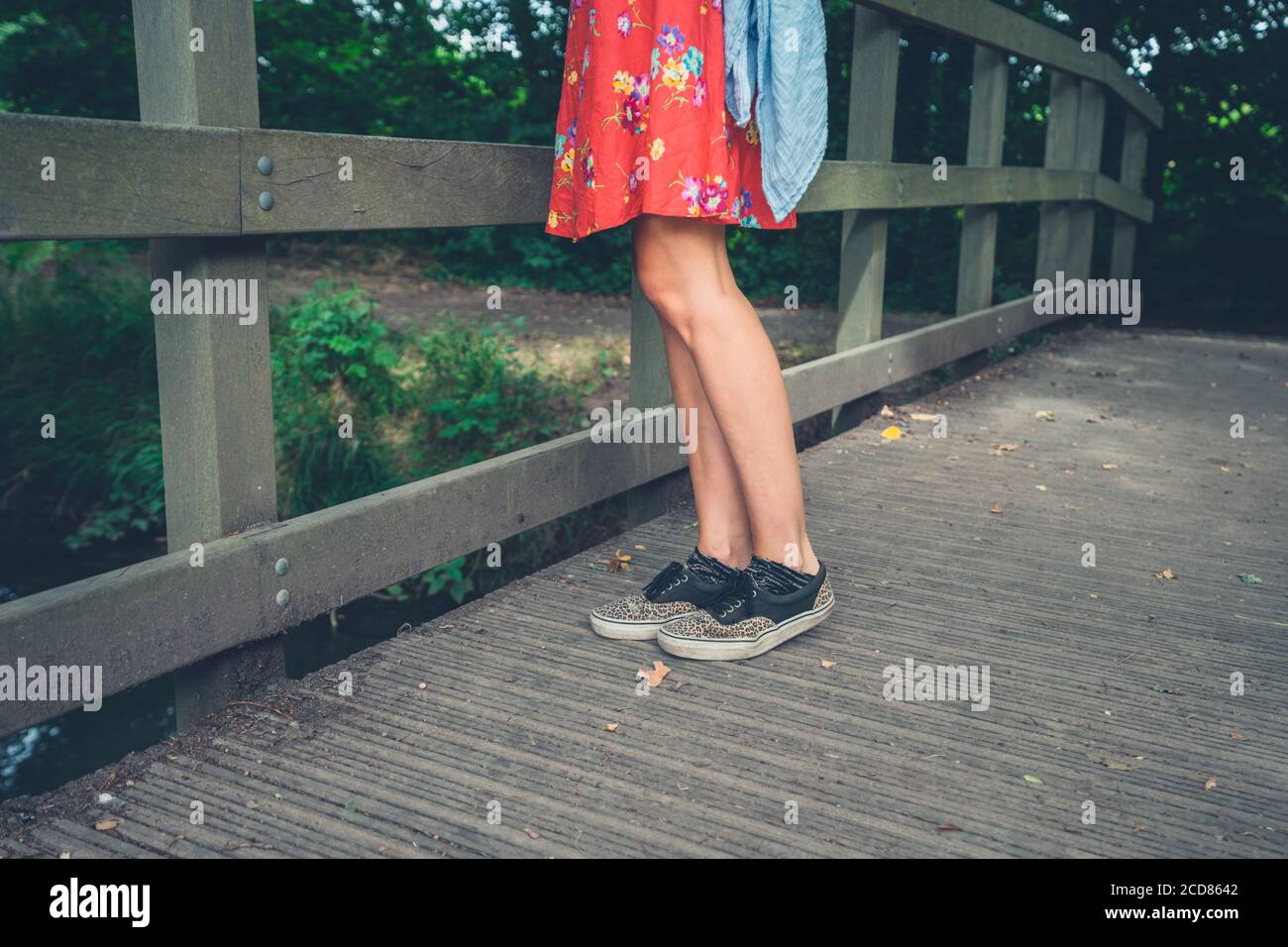 Les jambes d'une jeune femme debout sur un pont dans les bois Banque D'Images