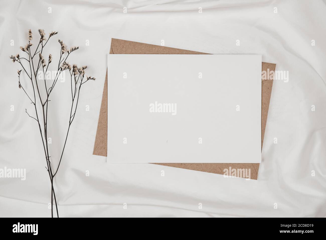 Papier blanc vierge sur enveloppe papier marron avec fleur sèche de Limonium sur tissu blanc. Maquette de carte de vœux vierge horizontale. Vue de dessus de Craft Envelo Banque D'Images