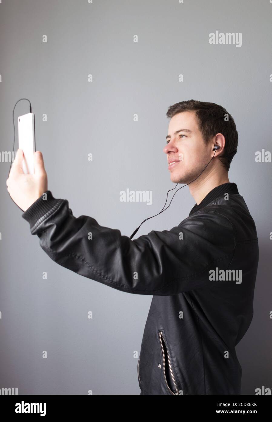 Jeune homme qui fait un appel vidéo avec son téléphone mobile et écouteurs Banque D'Images