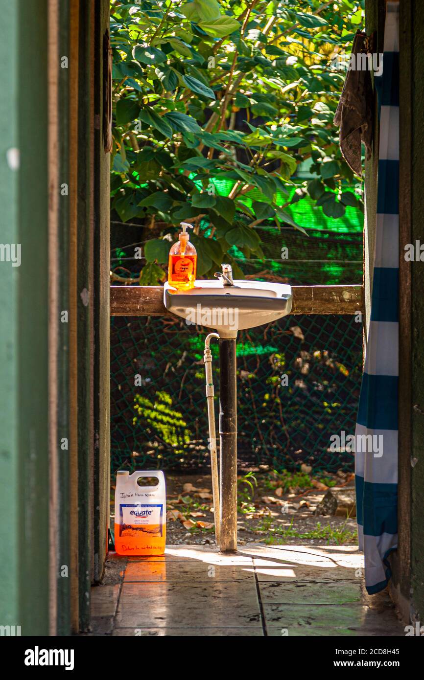 Projet de science citoyenne sur la biosphère pour la protection des tortues de mer au Costa Rica. Un lavabo autonome avec un distributeur de savon orange se trouve dans la zone de lavage couverte du camp, un bidon de recharge de savon pour les mains appuyé contre le sol, Reventazón, Costa Rica. Banque D'Images