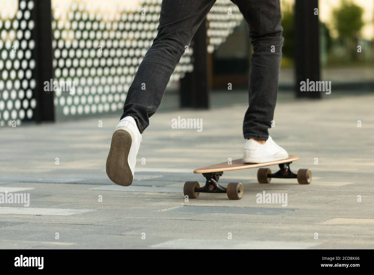 Homme skateboarder à cheval longue dans la ville, plein air, image rognée. Loisirs, mode de vie sain, sports extrêmes concept Banque D'Images