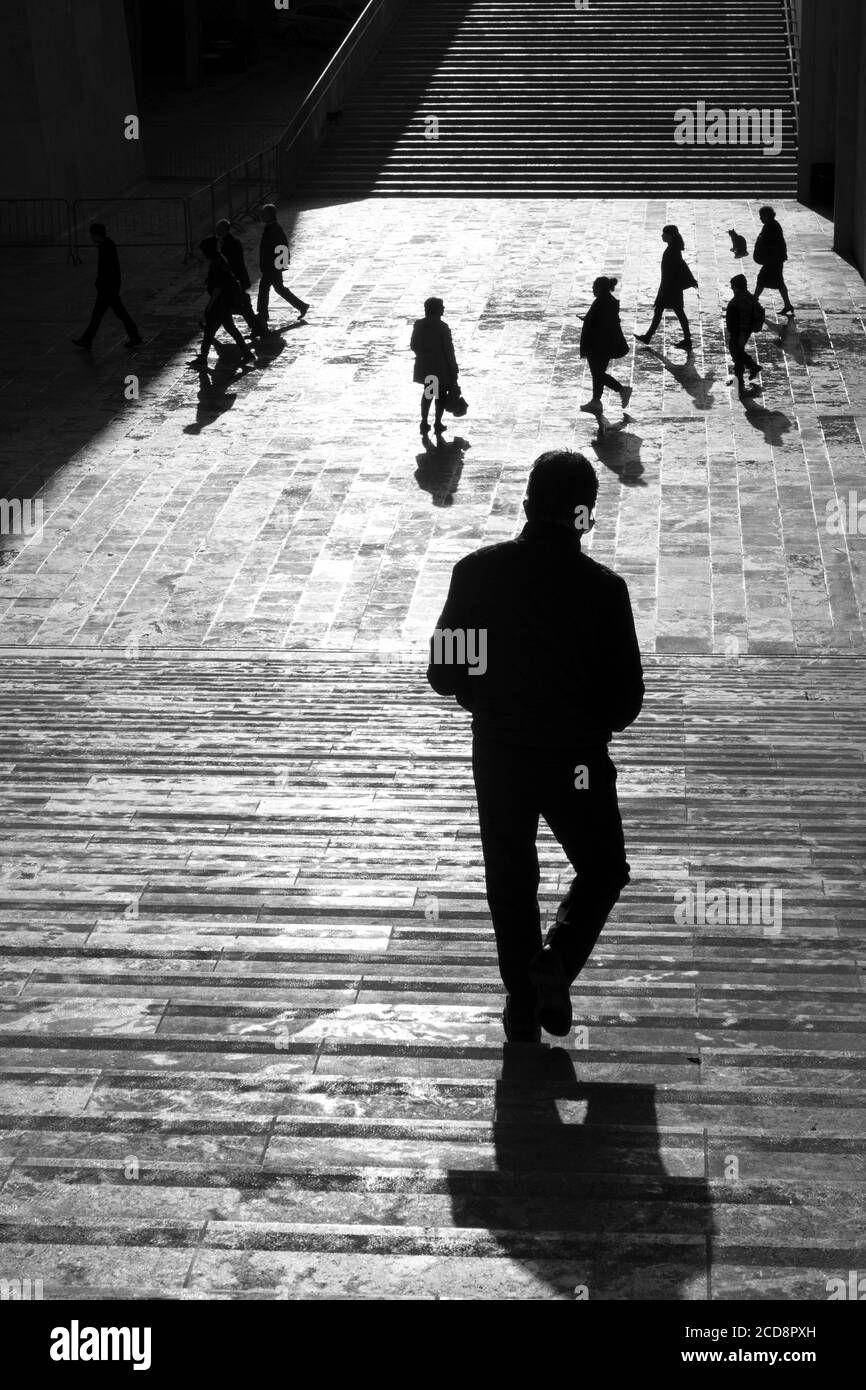 Silhouette d'une personne qui marche sur une place pavée de la ville Banque D'Images