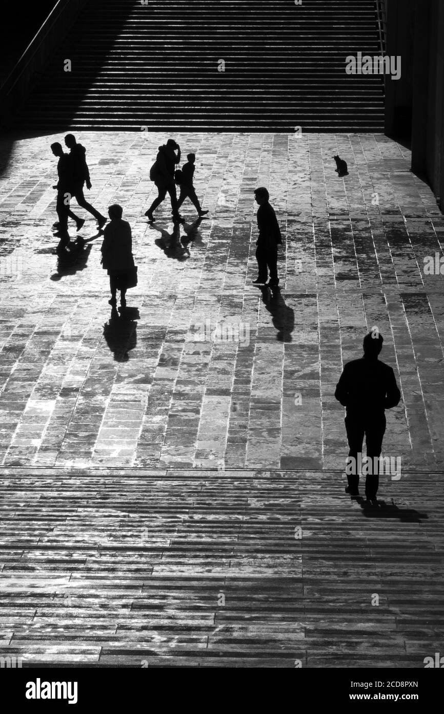Silhouette d'une personne qui marche sur une place pavée de la ville Banque D'Images