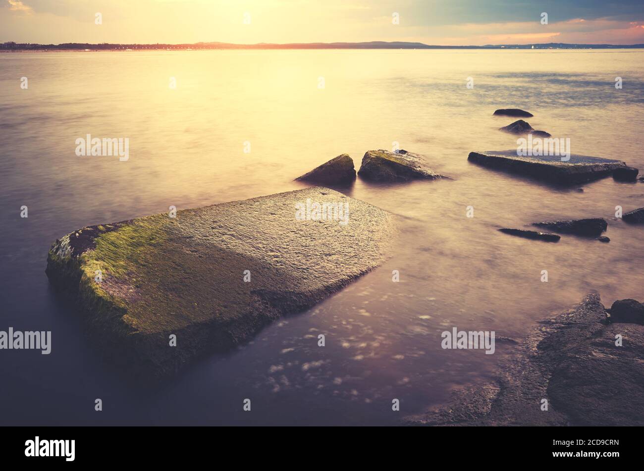 Rochers dans l'eau au coucher du soleil, couleurs appliquées, Swinoujscie, Pologne. Banque D'Images