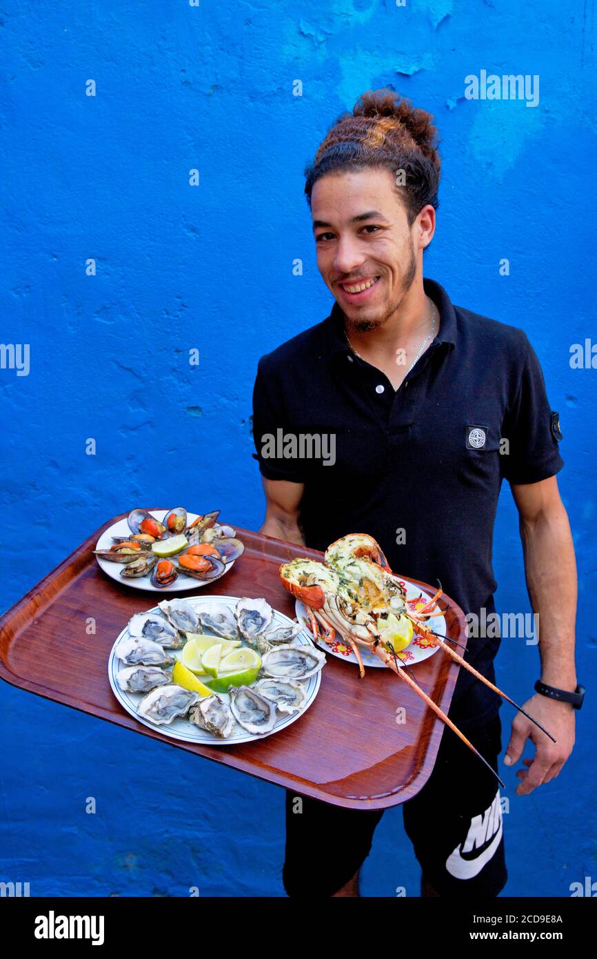 Maroc, Sahara occidental, Dakhla, serveur de restaurant Tal a mar avec une assiette d'huîtres et de fruits de mer Banque D'Images
