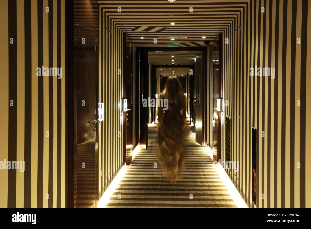 France, Paris, Hôtel Royal Monceau, femme en robe de soirée dans un couloir avec des motifs graphiques de Royal Monceau Banque D'Images