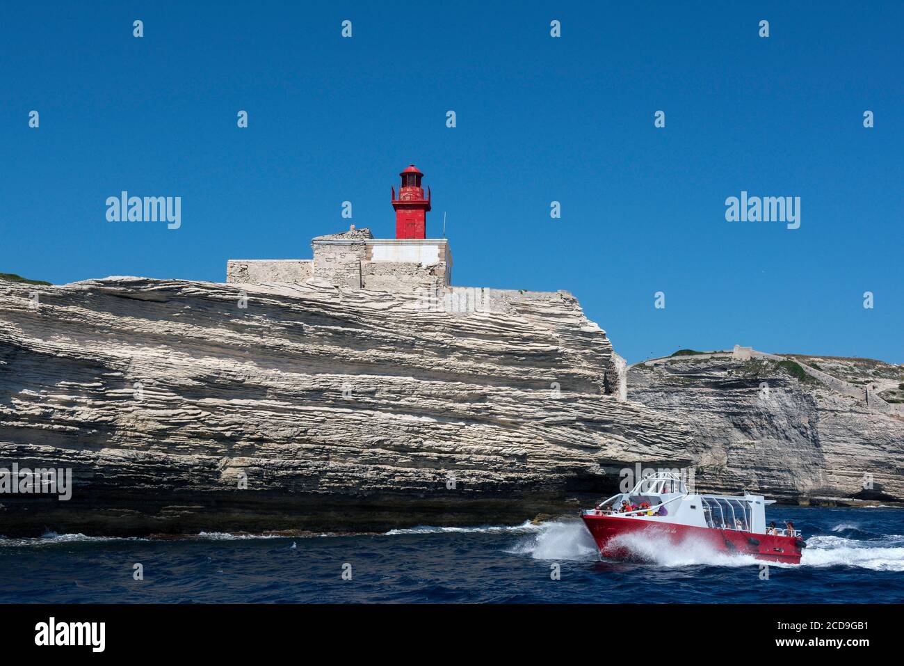 France, Corse du Sud, Bonifacio, les bateaux de promenade passent près du phare de Madonetta pour visiter la grotte de Sdragonato dont l'ouverture sur le ciel représente l'île de Corse Banque D'Images