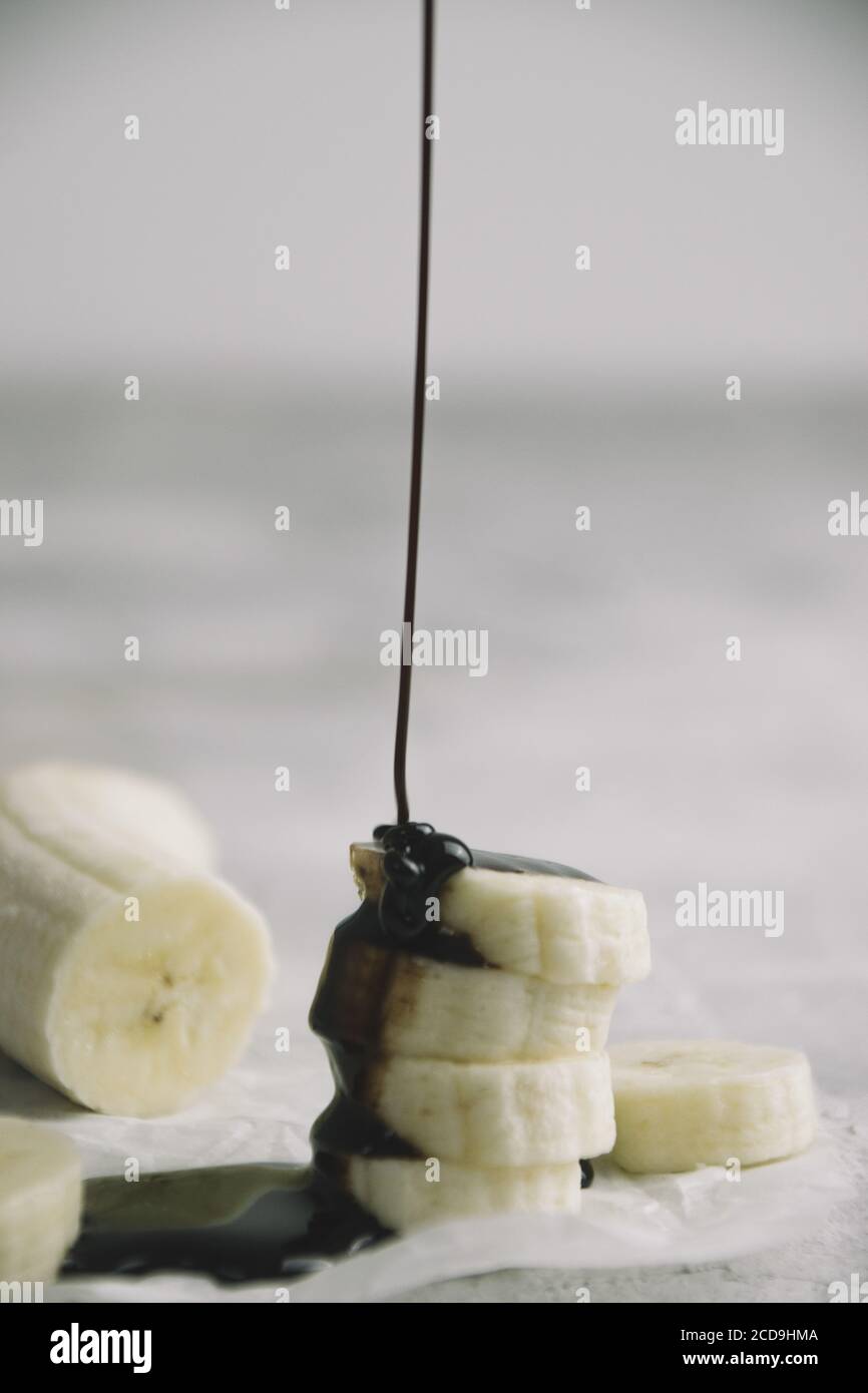 Injection verticale de tranches de banane tout en étant versé avec sirop de chocolat Banque D'Images
