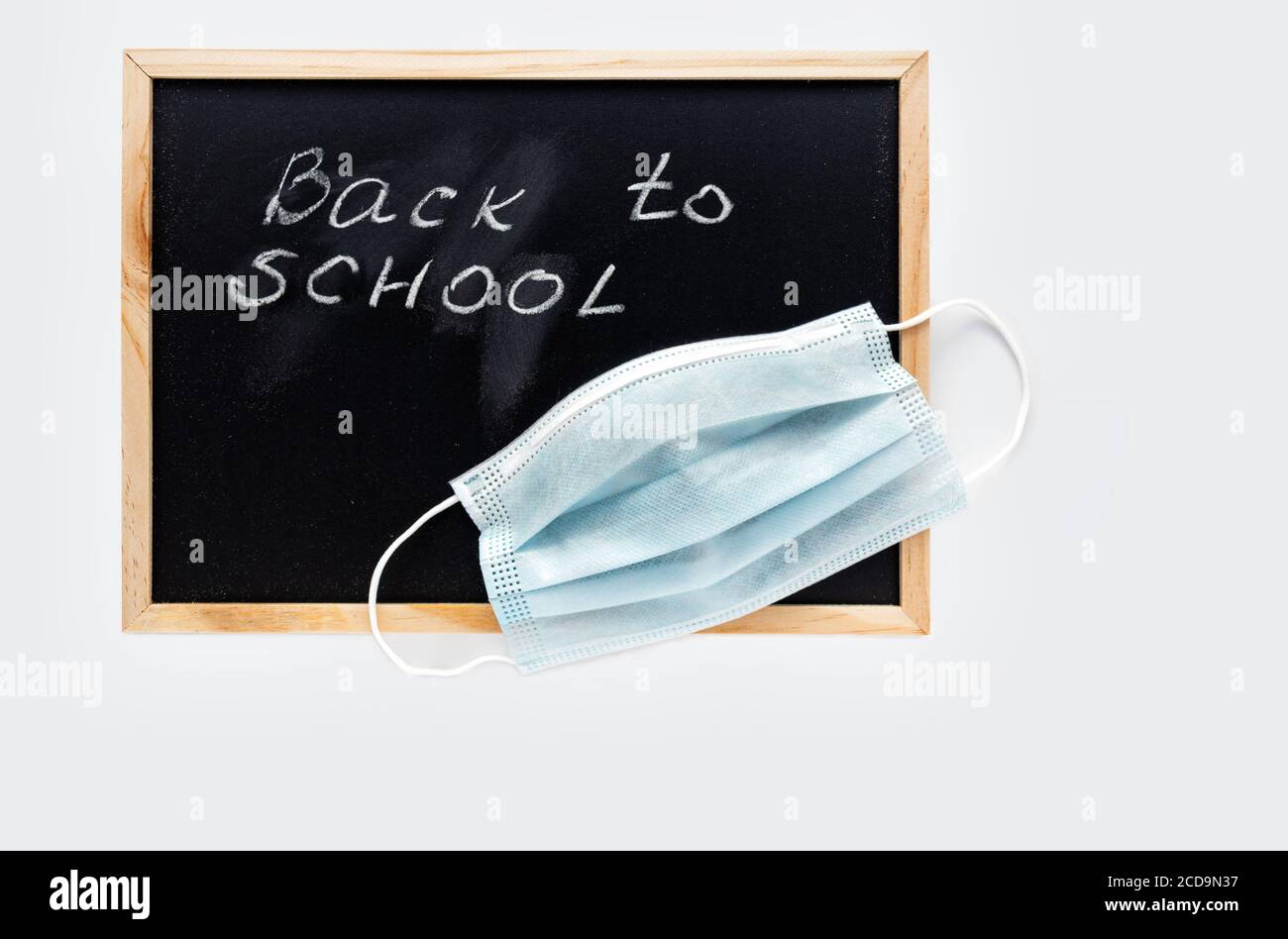 Retour à l'école lettrage et masque de protection médicale sur le tableau noir. Nouvelle année scolaire en 2020. Concept d'apprentissage, maintien de la distance sociale. Banque D'Images
