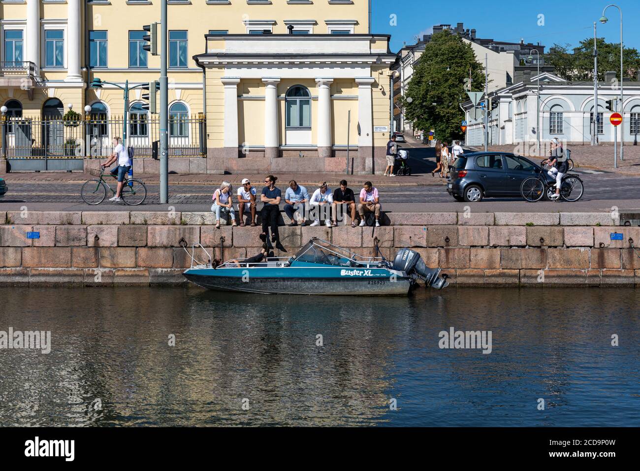 Jeunes adultes assis sur la rive du bassin devant le Palais présidentiel à Helsinki, en Finlande Banque D'Images