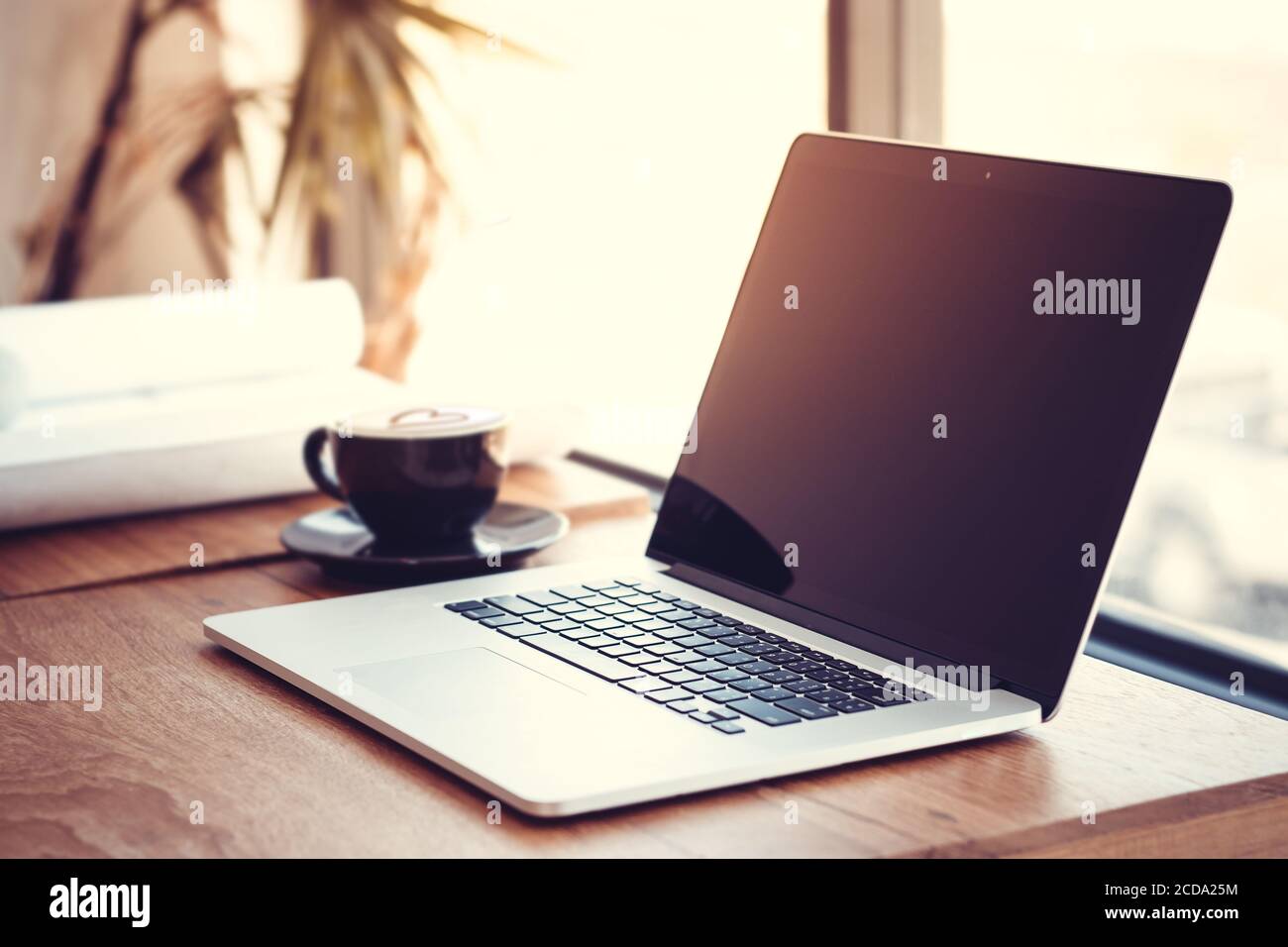 Travail de bureau avec ordinateur portable sur la table de bois contre les fenêtres. Banque D'Images
