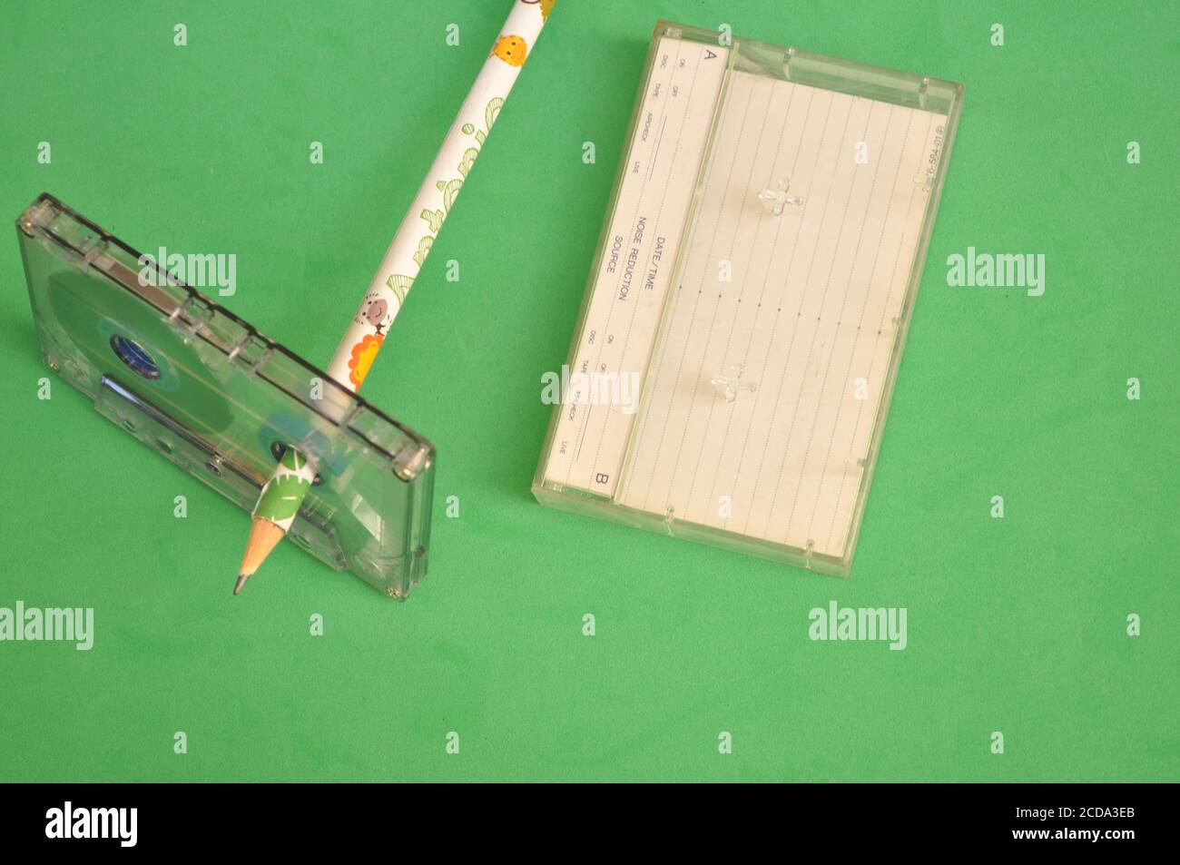Cassette audio avec crayon de couleur utilisé pour envelopper le collez la bande sur un arrière-plan vert avec la vue de dessus Banque D'Images
