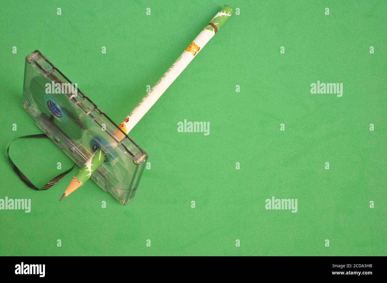 Cassette audio avec crayon de couleur utilisé pour envelopper le collez la bande sur un arrière-plan vert avec la vue de dessus Banque D'Images