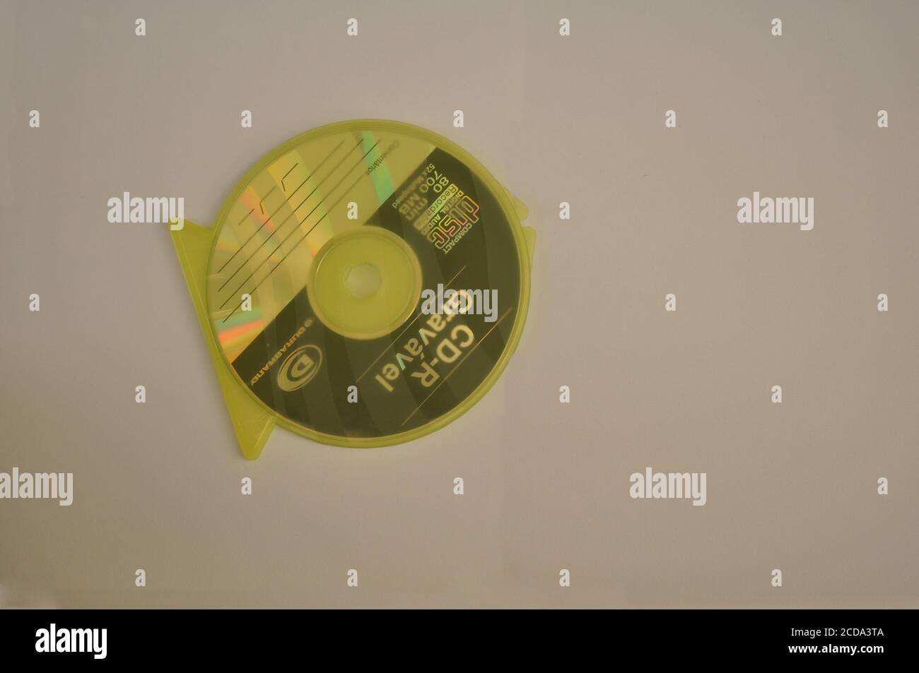 Disque compact pour l'enregistrement de données dans un couvercle en plastique jaune vue de dessus en forme de poisson sur fond blanc Banque D'Images