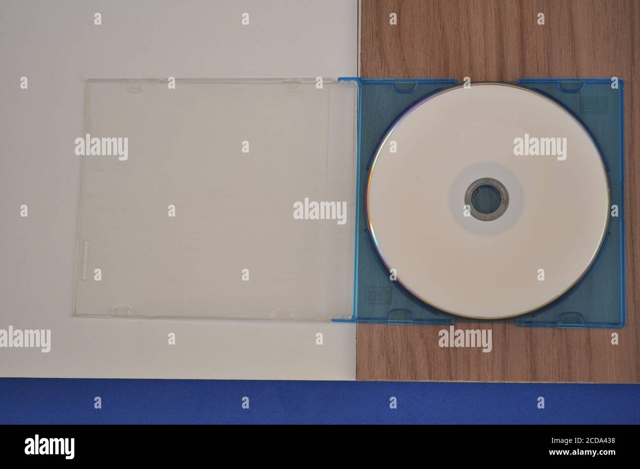 DVD avec couvercle acrylique sur fond blanc, bleu et bois Banque D'Images