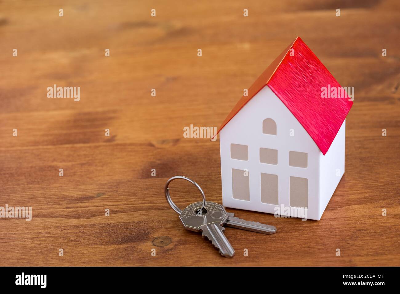 Gros plan d'un modèle de maison et des clés sur une table rustique en bois. Concept d'achat immobilier résidentiel. Banque D'Images
