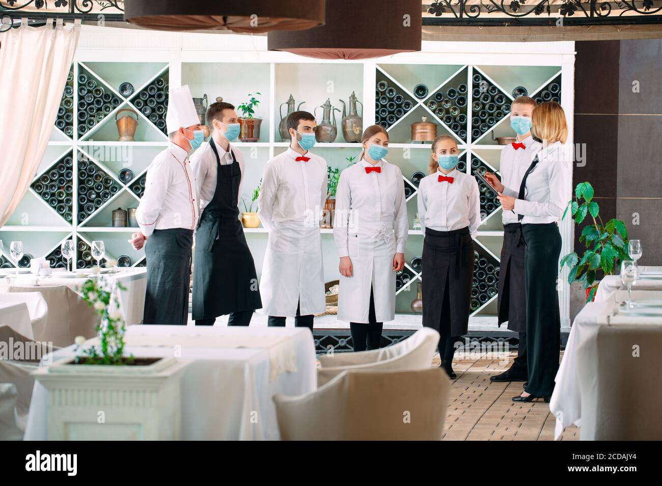 Employés d'un restaurant ou d'un hôtel dans des masques de protection. Fin de la quarantaine. Le directeur du restaurant et son personnel sur la terrasse. Interaction avec le chef Banque D'Images