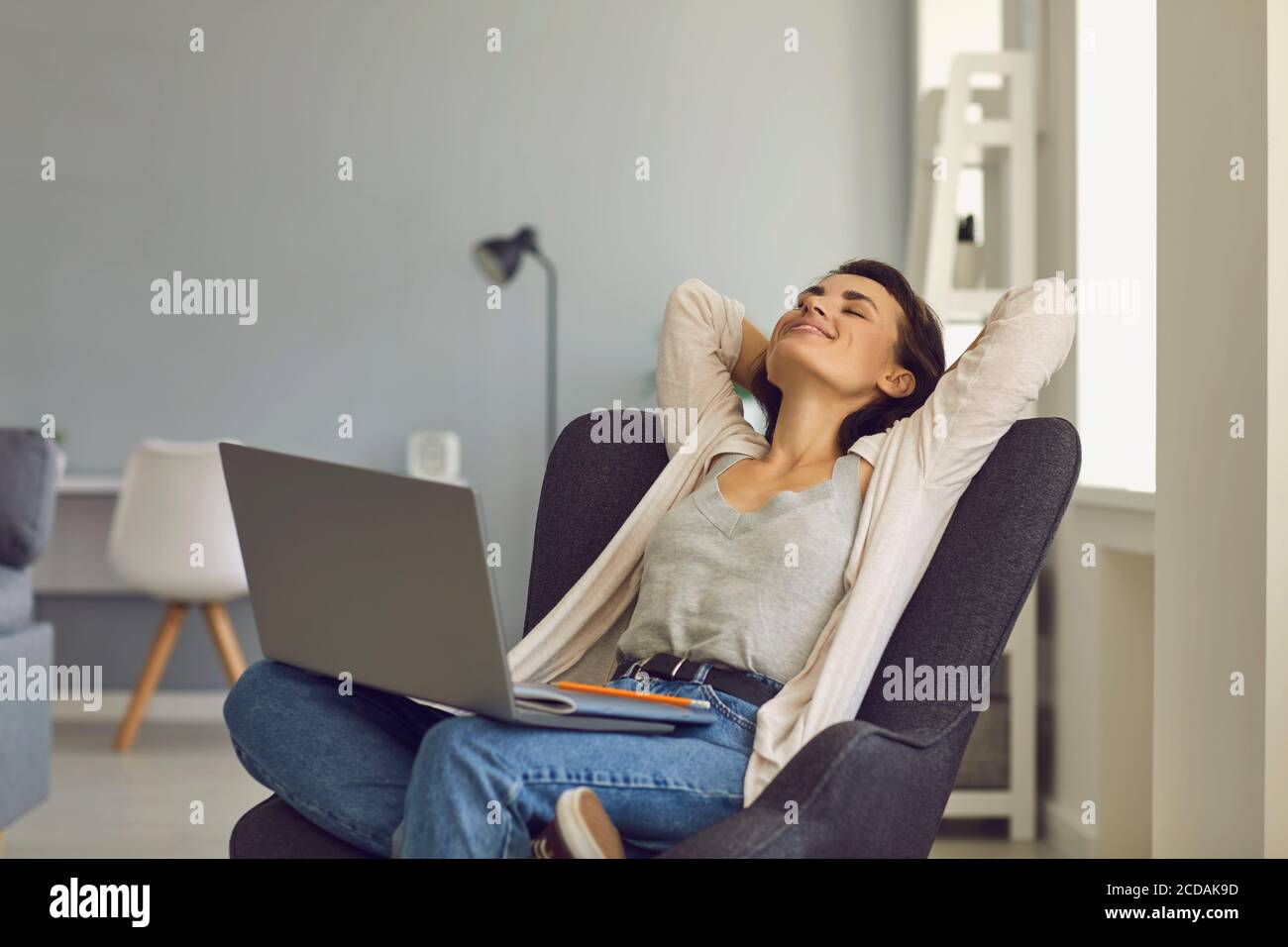 Femme souriante assise avec un ordinateur portable et se sentant heureuse en ligne conversation Banque D'Images