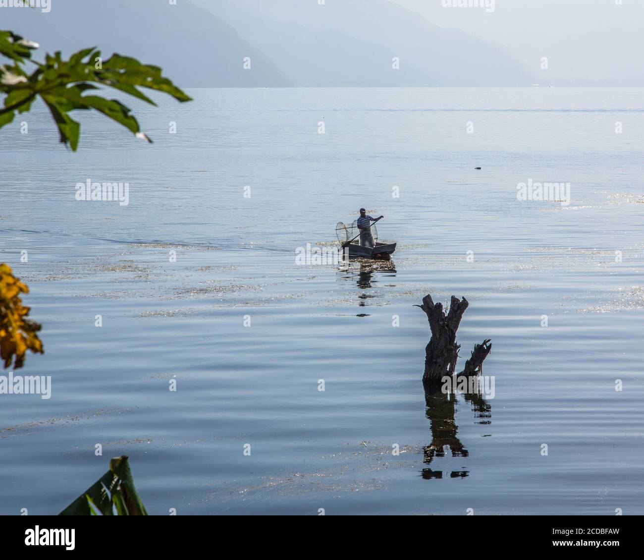 Un pêcheur maya avec son fishtrap en fil dans son cayuco ou canoë sur le lac Atitlan par San Pedro la Laguna, Guatemala. Les eaux de lac montantes depuis 2009 ont Banque D'Images